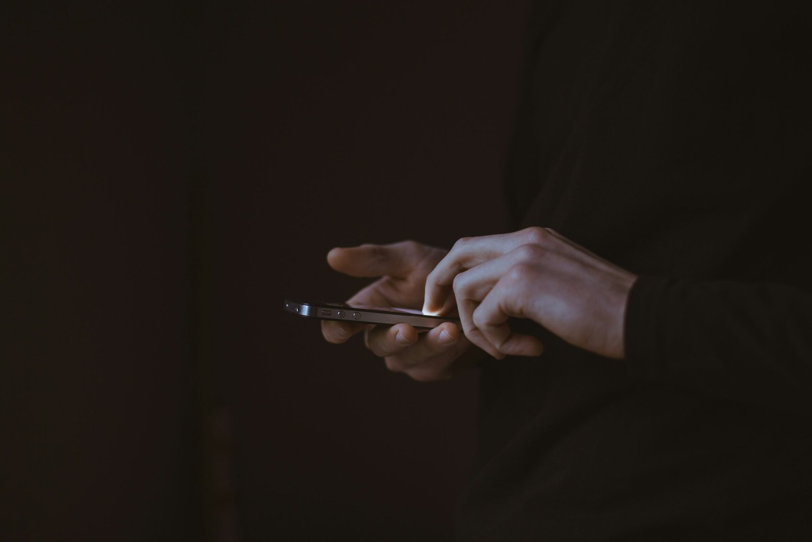 Hand using a smartphone in a dark environment symbolizing false base station attacks and mobile network exploitation in Asia-Pacific