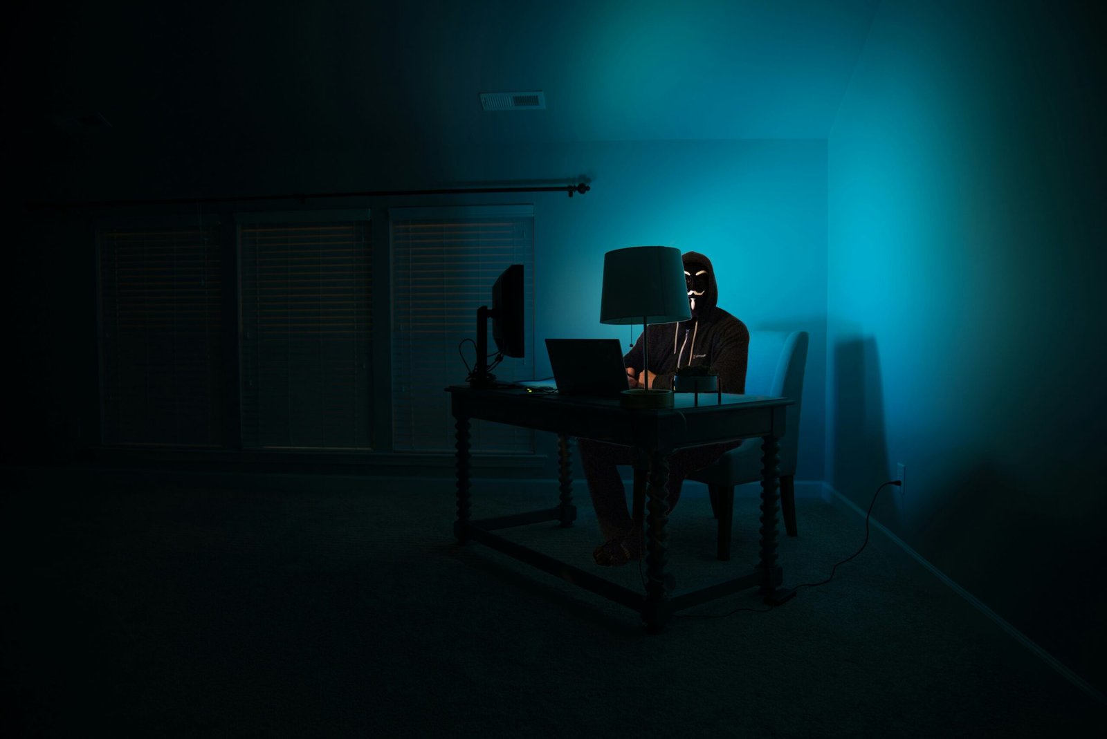 Person working on a computer in a dark room symbolizing common hacker tactics and cyberattack methods